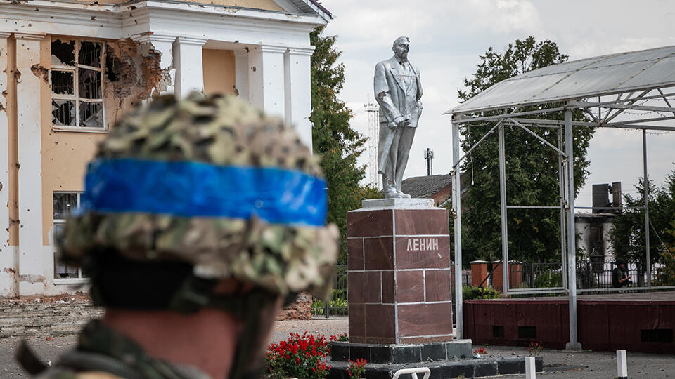 Украинский солдат смотрит на памятник Ленину в центре Суджи